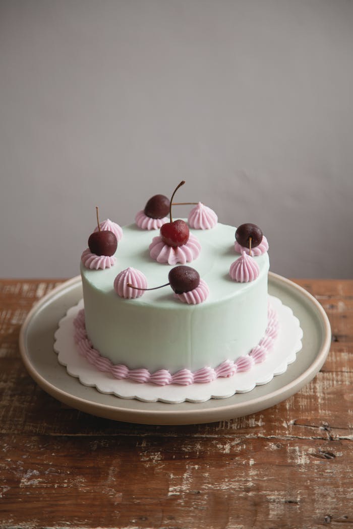 A beautifully decorated cake with cherries and pink frosting, perfect for celebrations.